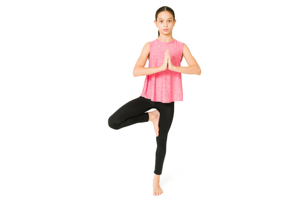 Chica joven enfocada haciendo ejercicio y con un buen equilibrio corporal. Chica deportiva y atlética haciendo ejercicio con yoga - Foto, Imagen