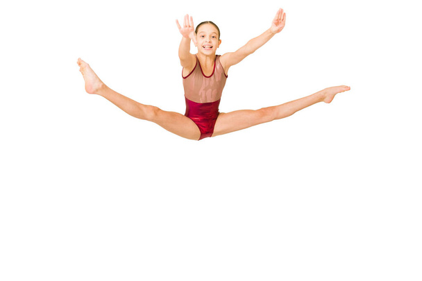 Возбужденный спортивный гимнаст улыбается во время прыжка и делает разрыв ноги. Веселая девушка, выступающая на спортивных соревнованиях - Фото, изображение