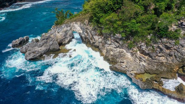 Aerial top view of white waves in blue sea hit on the large rocks in summer day. Beach sea space area. blue sea, waves crashing on the rocks. Nusa Penida, Bali. - Fotó, kép