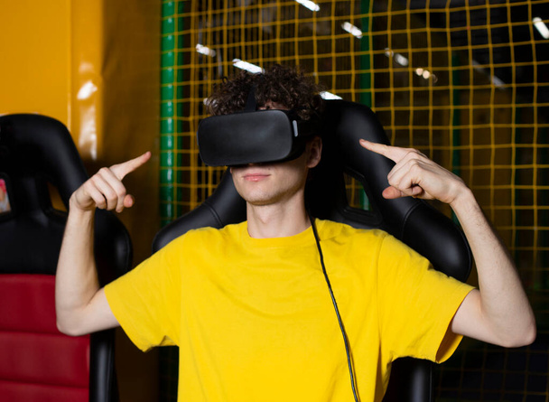 Young man wearing VR glasses and pointing at something in the game. 3D technology. Virtual reality glasses - Photo, Image