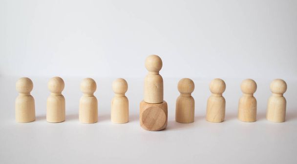 The chosen person among others. A human figure of green color stands out from the crowd. Wooden figures of people. A talented worker, a successful choice. Promotion. Concept of search for worker. - Photo, Image