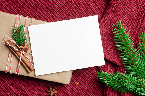 Vánoční přání mockup s zdobené dárkové krabice a jedle větev stromu na červeném pleteném pozadí - Fotografie, Obrázek