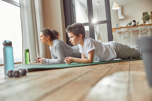 Sporty mom training core with son at home - Photo, Image