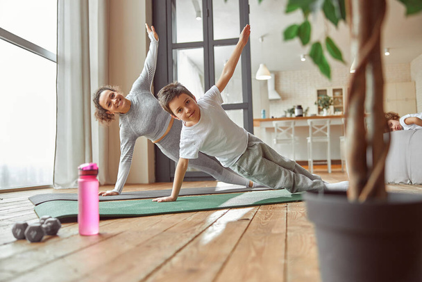 Active mother doing workout with son at home - Foto, afbeelding