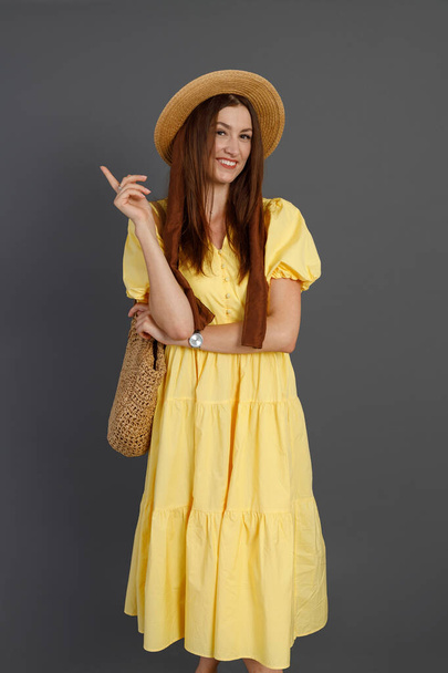 Χαρούμενη γυναίκα με κίτρινο φόρεμα στέκεται στο στούντιο - Φωτογραφία, εικόνα
