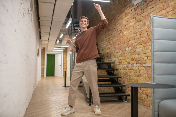 A young man looking happy and enjoyed in the office corridor - Foto, afbeelding