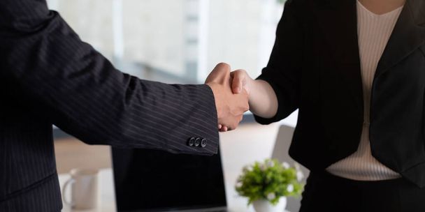 Business people handshake at meeting table in office together with confident . Young businessman and businesswoman workers express agreement of investment deal - Φωτογραφία, εικόνα