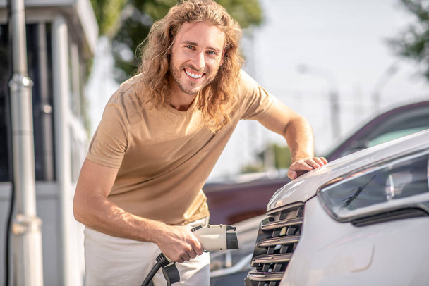 Cheerful affable young man cleaning car - Foto, imagen
