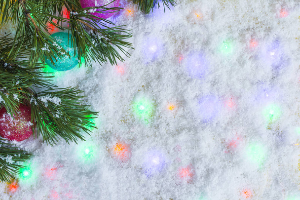 Festive New Year background artificial snow and colored lights with fir branches place for text. - Foto, imagen