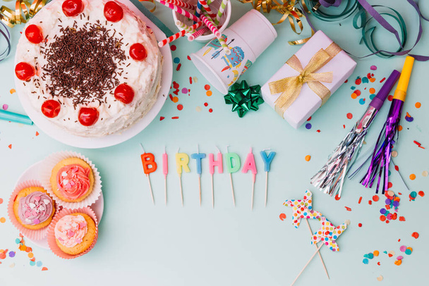 palabra cumpleaños velas partido accesorios pastel telón de fondo azul. Foto de alta calidad - Foto, imagen