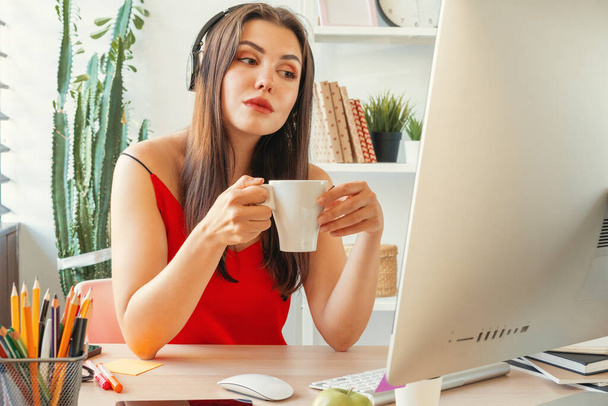 Young woman having a coffee break while sitting in her office - Foto, immagini