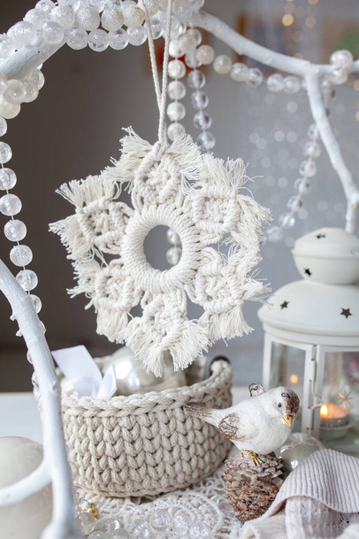 Beautiful New Year's decor using macrame technique. Handmade, Macrame cord snowflake hanging on a white branch - Фото, изображение