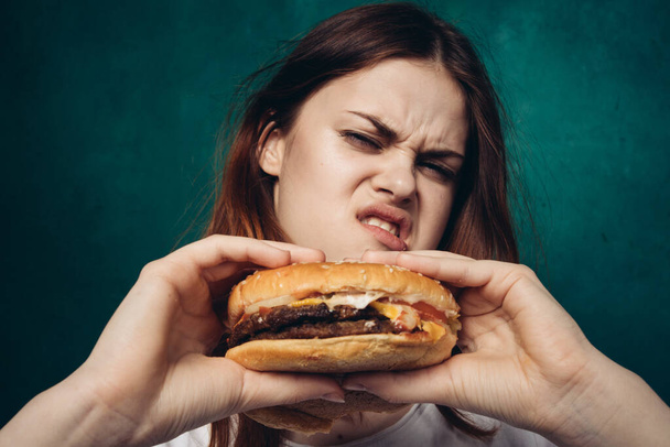 cheerful woman with hamburger near face snacking fast food - Foto, imagen