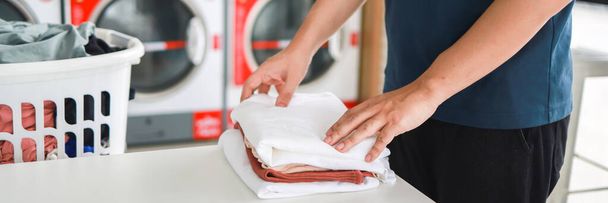 Człowiek robiący kosz na pranie z brudnym praniem pralki w publicznym sklepie. ubrania do prania  - Zdjęcie, obraz