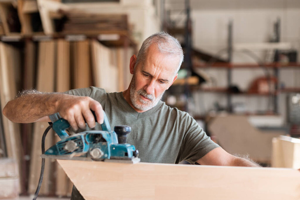 Man planing wood with a hand planer - Photo, image
