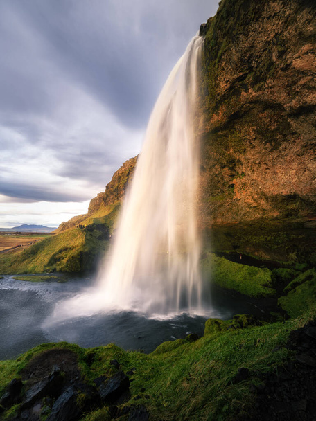 A vertical shot of a scenic waterfall flowing down the high cliff in Iceland - Fotoğraf, Görsel