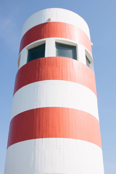 A vertical shot of a tall red white lighthouse structure on a pier - Foto, imagen