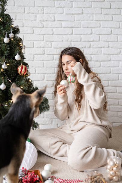 mujer atractiva joven decorando el árbol de Navidad y jugando con perros - Foto, Imagen