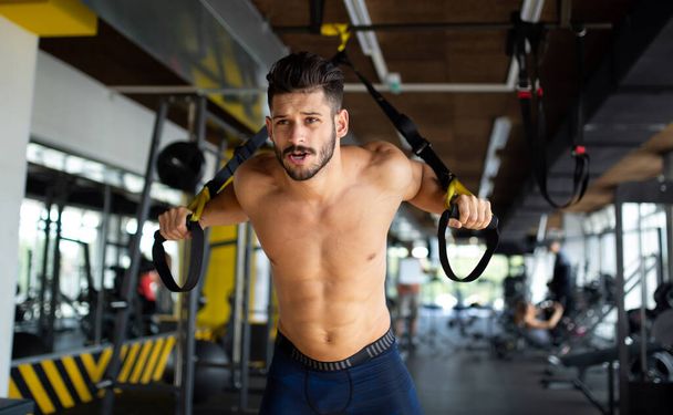 Young handsome fit man exercising in a gym. Sport people healthy lifestyle concept - Foto, immagini
