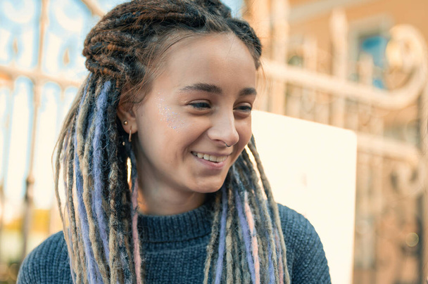 Portrait of a young woman with dreadlocks. Pretty friendly young caucasian woman outdoor - Photo, Image