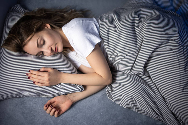 Csinos, fiatal nő alszik az ágyában késő reggel egy hétvégén - kompenzálja az alváshiányt - Fotó, kép
