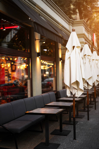 restaurant terrasse sans personnes. canapés gris confortables et parasols blancs sur la terrasse d'été d'un établissement fermé - Photo, image