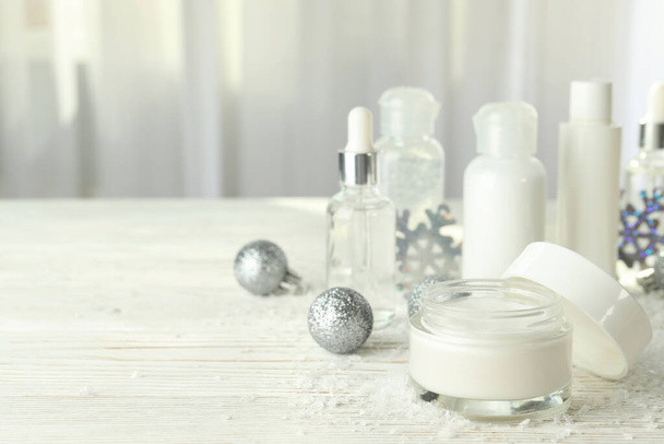 Композиція з зимовими косметичними виробами на білому дерев'яному столі
 - Фото, зображення