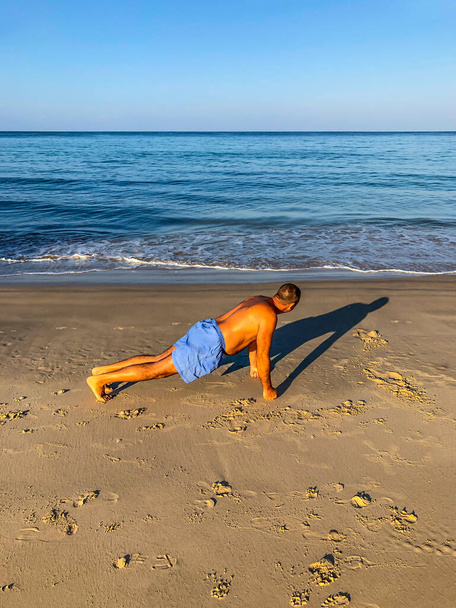 a man goes in for sports, does exercises on the seashore - Фото, зображення