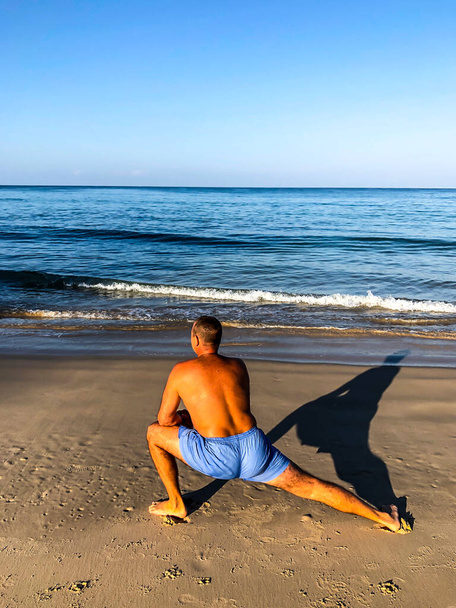 a man goes in for sports, does exercises on the seashore - Photo, Image