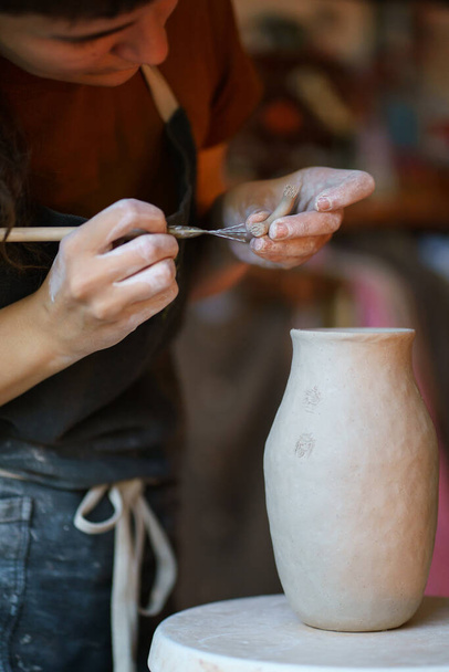 Produzione ceramica: l'artista utilizza strumenti professionali per modellare argilla grezza e creare vasai in studio - Foto, immagini