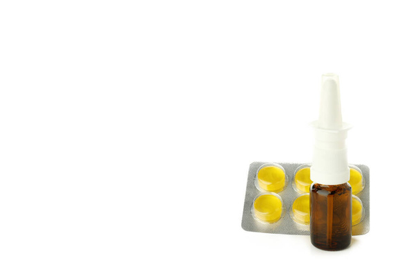 Λευκό μπουκάλι ρινικού ψεκασμού και χάπια που απομονώνονται σε λευκό φόντο - Φωτογραφία, εικόνα