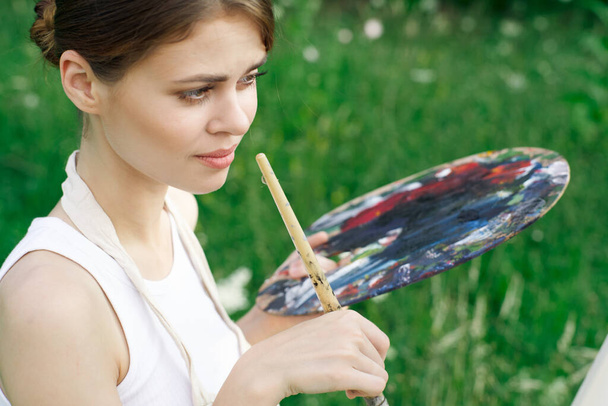 Woman in white dress with palette of paints on nature art drawing - Photo, Image