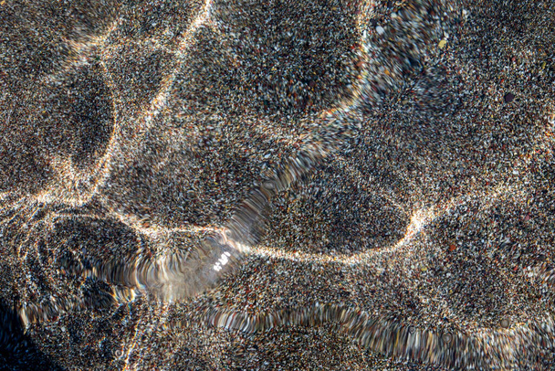 fondo abstracto borroso de agua transparente del mar con olas y fondo arenoso con rayos reflejados del sol, horizontal - Foto, imagen