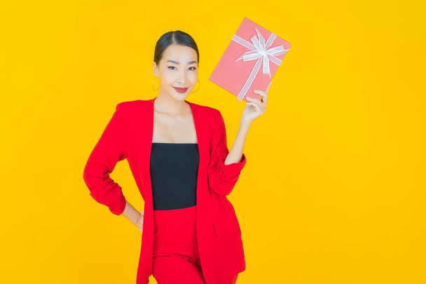 Portrait beautiful young asian woman smile with red gift box on color background - Fotografie, Obrázek