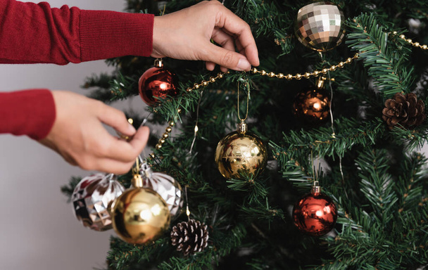 Γυναίκα διακόσμηση χριστουγεννιάτικο δέντρο με στολίδια την ημέρα των Χριστουγέννων. - Φωτογραφία, εικόνα