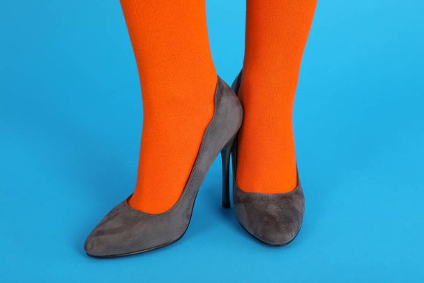 Female legs in orange socks and in heels on blue background - Фото, зображення
