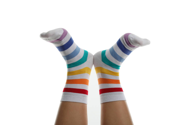 白い背景に隔離された虹の靴下の女性の足 - 写真・画像