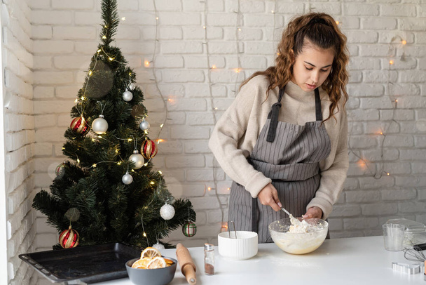 Улыбающаяся женщина на кухне печет рождественское печенье - Фото, изображение