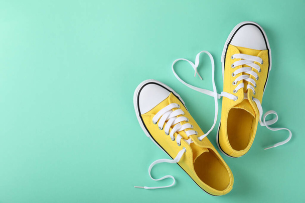 Pair of yellow sneakers on mint background - Photo, Image