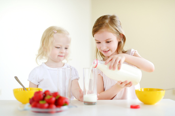 Sisters eating cereal with milk - Foto, afbeelding