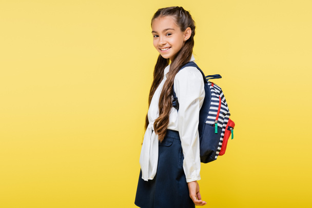 Happy preteen child with backpack looking at camera isolated on yellow  - Zdjęcie, obraz
