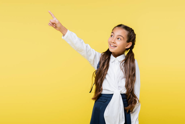 Happy pupil in shirt pointing with finger isolated on yellow  - Fotoğraf, Görsel