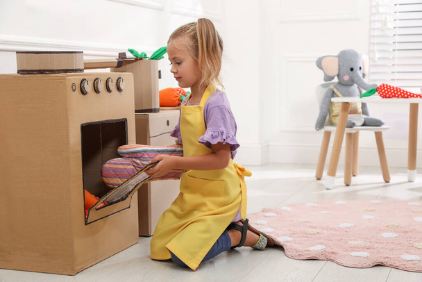 Little girl playing with toy cardboard oven at home - Photo, Image