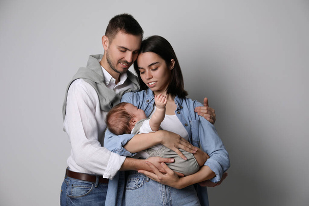 Happy family. Couple with their cute baby on grey background - Fotó, kép