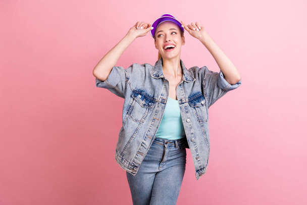 Photo of cool blond millennial lady look empty space wear blue top jacket visor isolated on pink color background - Photo, Image