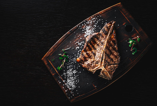Grilled T-bone Steak on bones on wooden board on dark background - Fotoğraf, Görsel