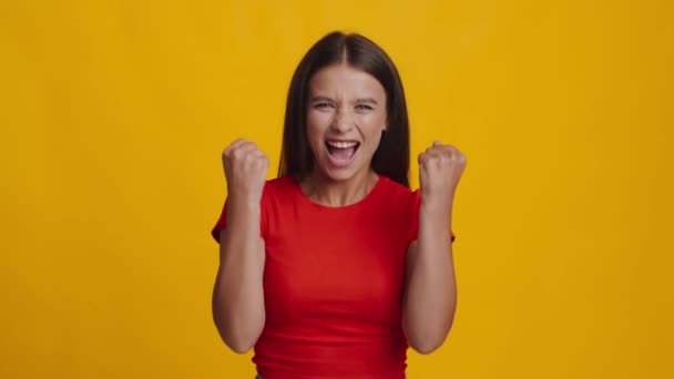 vrouw schreeuwen en schudden vuisten in vreugde over gele achtergrond - Video