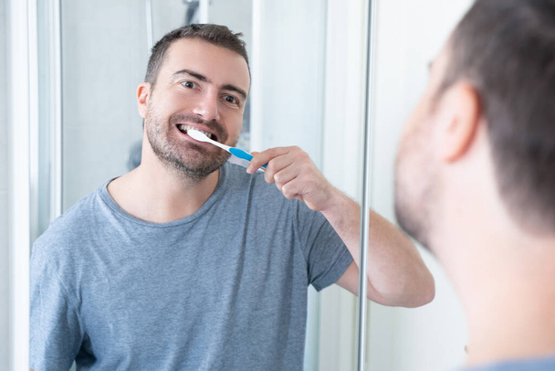 Een man doet mondhygiëne met behulp van tandenborstel in de ochtend - Foto, afbeelding