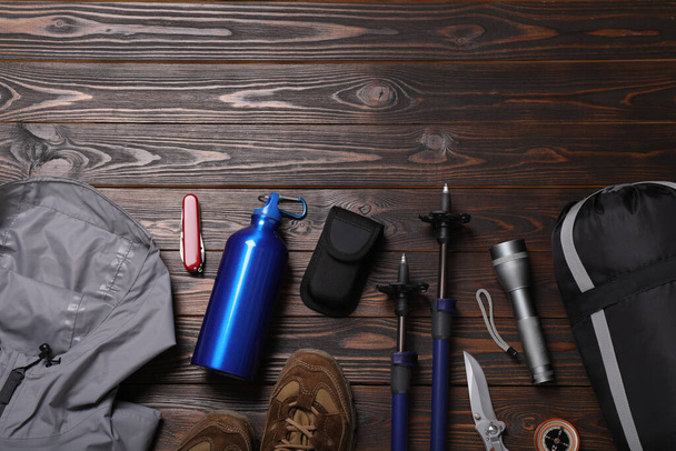 Flat lay composition with trekking poles and other hiking equipment on wooden background, space for text - 写真・画像