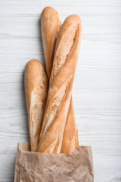 Tasty baguettes in package on white wooden table, top view - Foto, immagini